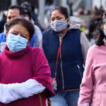 Personas con cubrebocas, chamarras y guantes transitan por el primer cuadro de la ciudad
